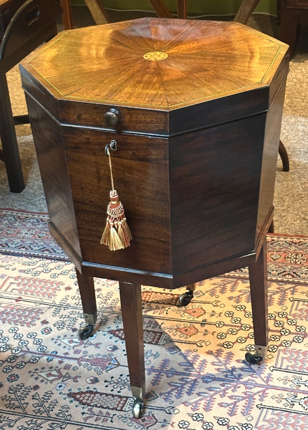 An octagonal George III mahogany cellarette on tapered legs with brass castors, featuring a starburst veneered lid and inlaid detailing.