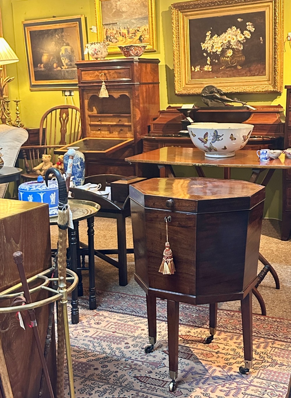 An octagonal George III mahogany cellarette on tapered legs with brass castors, featuring a starburst veneered lid and inlaid detailing. View VI