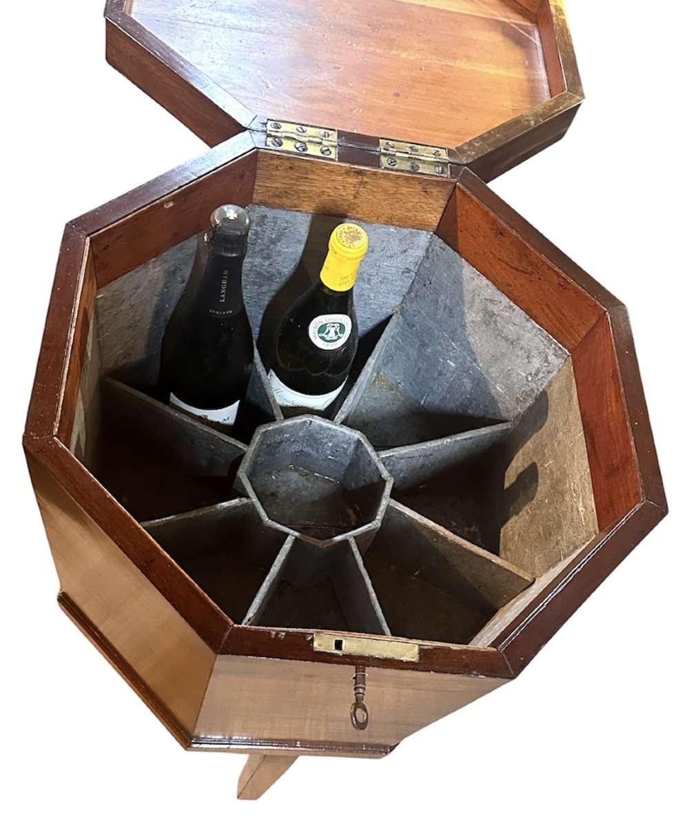 An octagonal George III mahogany cellarette on tapered legs with brass castors, featuring a starburst veneered lid and inlaid detailing. View VII