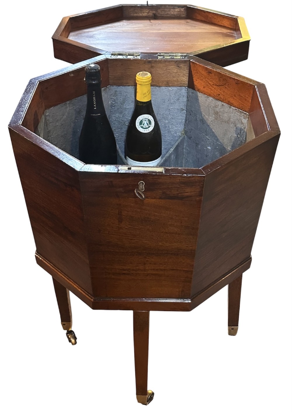 An octagonal George III mahogany cellarette on tapered legs with brass castors, featuring a starburst veneered lid and inlaid detailing. View IX