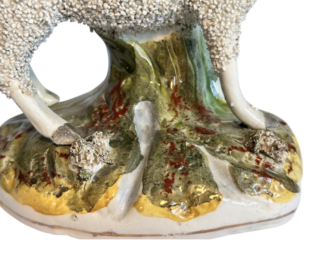A pair of Victorian Staffordshire earthenware spill vases depicting textured woolly sheep standing alongside green tree trunk vessels. View VI