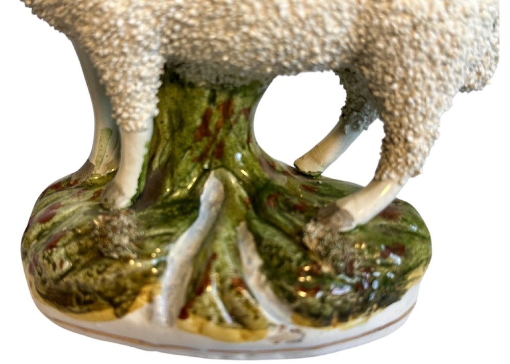 A pair of Victorian Staffordshire earthenware spill vases depicting textured woolly sheep standing alongside green tree trunk vessels. View VII