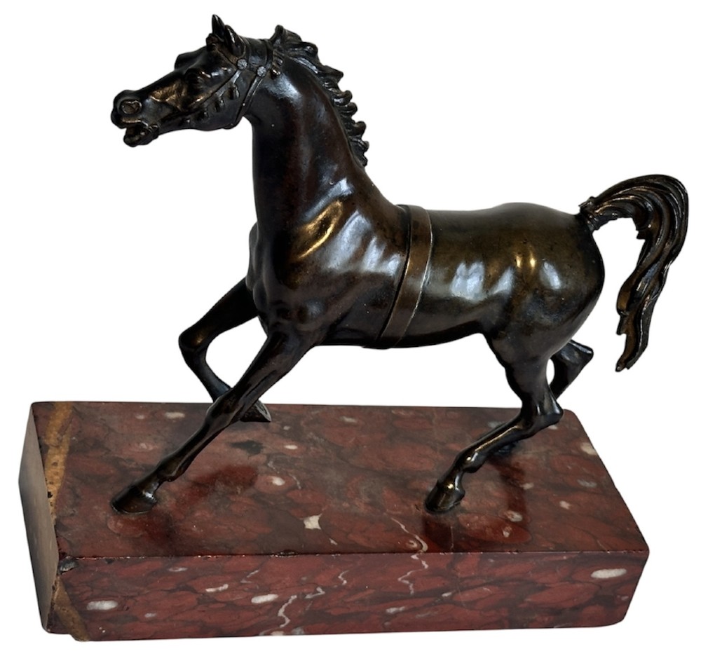 A dark patinated bronze sculpture of a trotting stallion mounted on a rectangular veined red marble plinth. View V