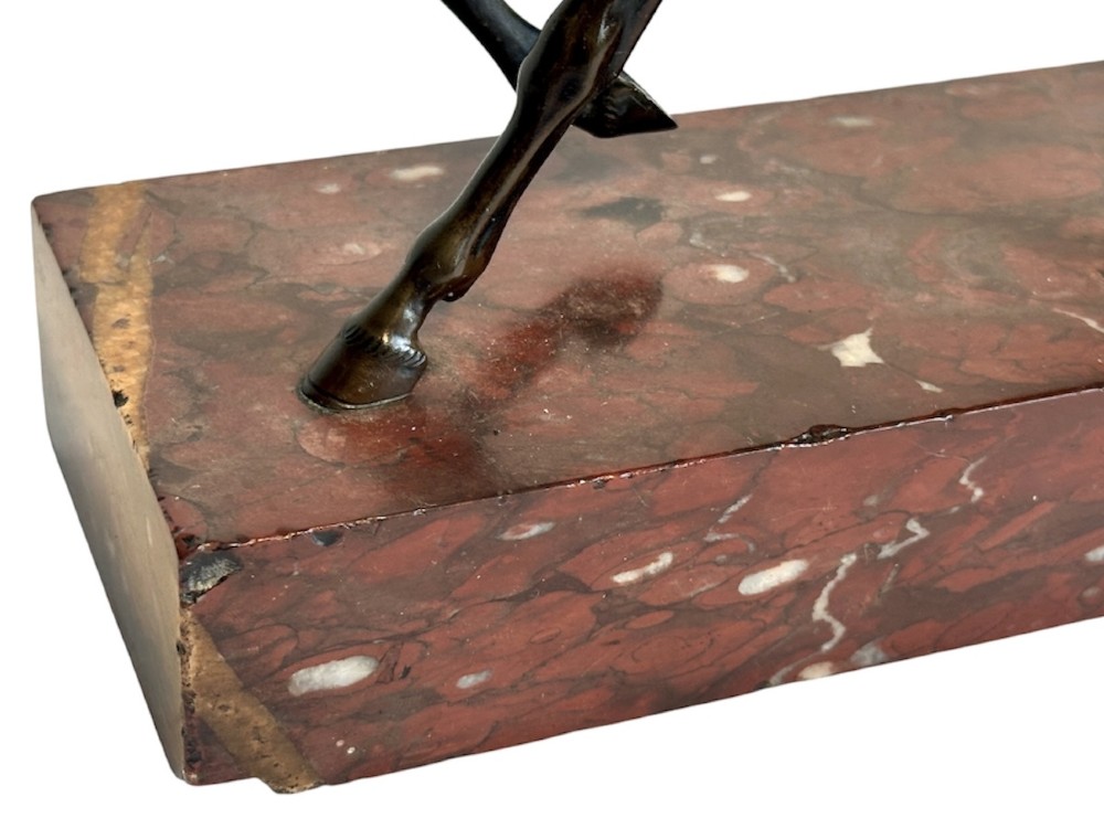 A dark patinated bronze sculpture of a trotting stallion mounted on a rectangular veined red marble plinth. View VII