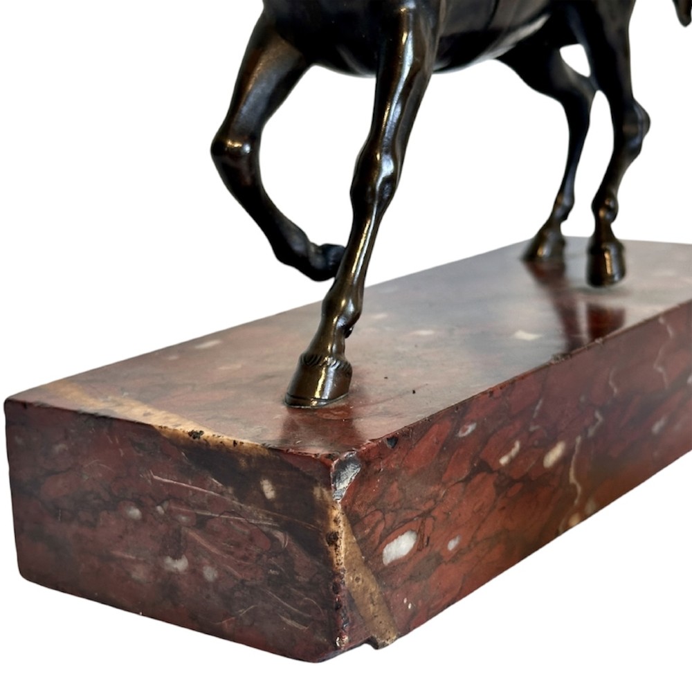 A dark patinated bronze sculpture of a trotting stallion mounted on a rectangular veined red marble plinth. View X