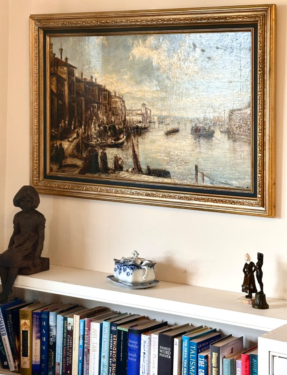 An antique oil painting depicting a Venetian canal with gondolas and historical buildings under a cloudy sky, enclosed in an ornate gold frame. View IX