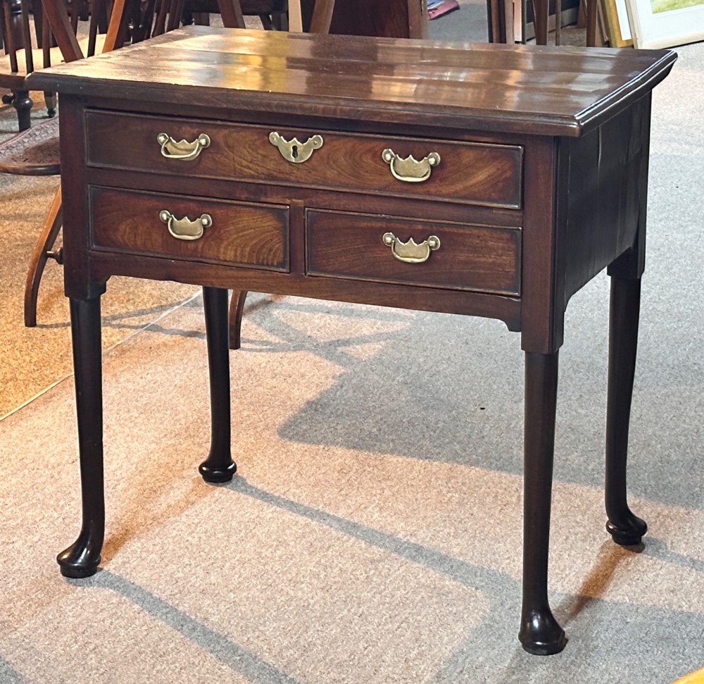 A George III mahogany lowboy featuring three brass-handled drawers, shaped aprons, and slender legs ending in pad feet. View II