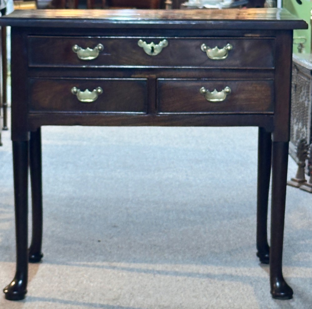 A George III mahogany lowboy featuring three brass-handled drawers, shaped aprons, and slender legs ending in pad feet. View VII