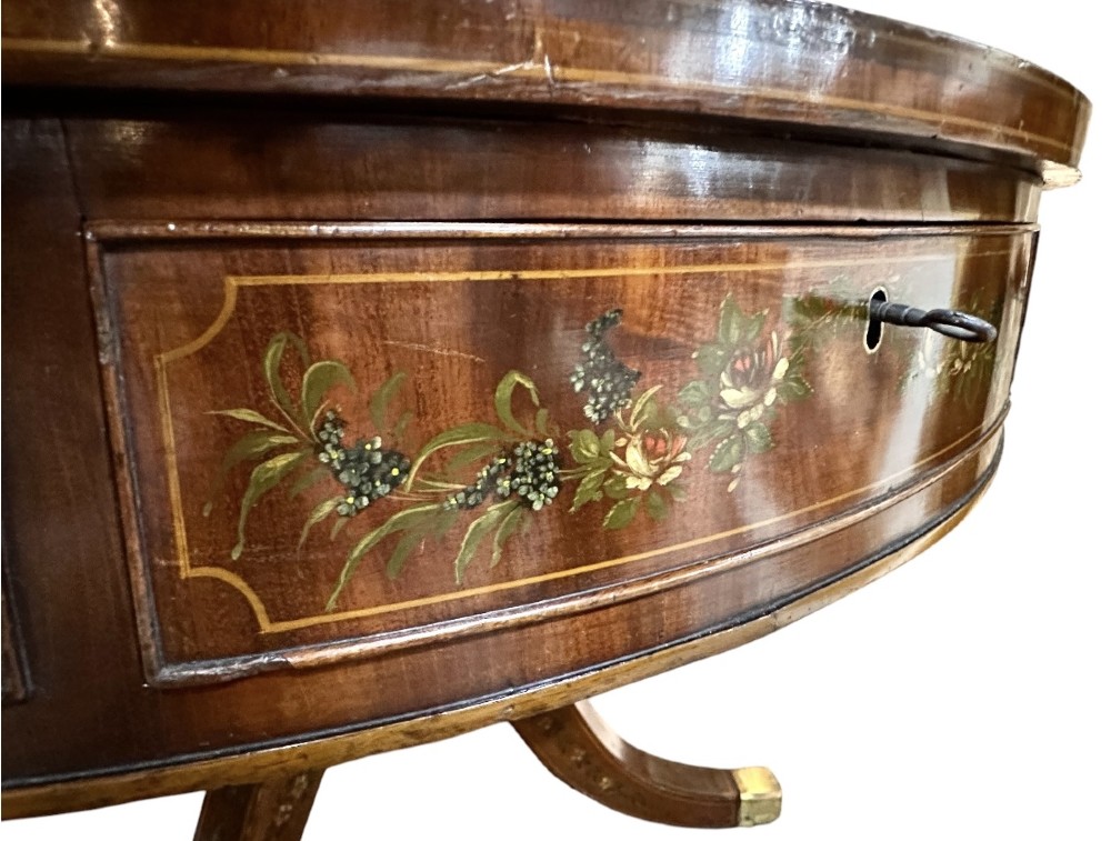 A circular antique mahogany drum table featuring a brown leather inset top, painted floral frieze drawers, and a central pedestal base on splayed legs with brass castors. View IX