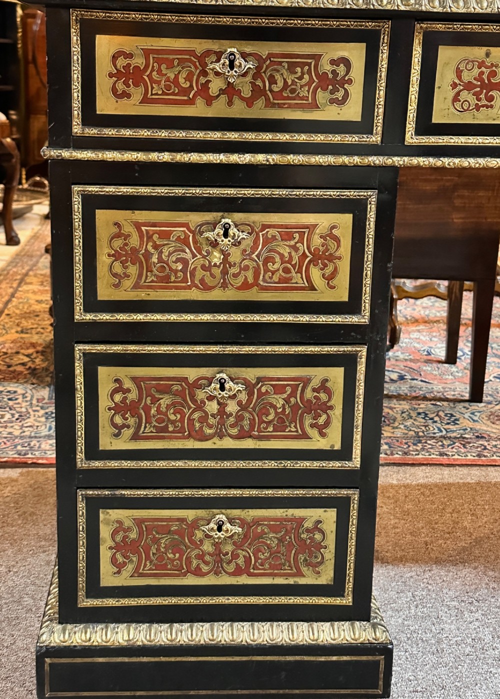 An ebonised French pedestal desk featuring red tortoiseshell and brass Boulle marquetry inlay, multiple drawers, a leather writing top, and a brass gallery. View IX