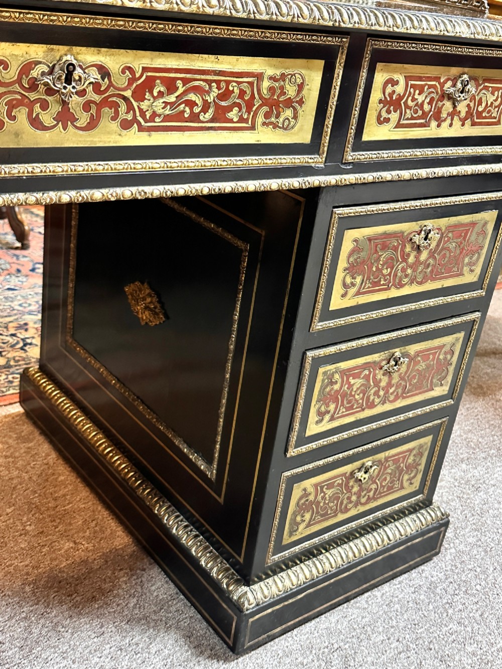 An ebonised French pedestal desk featuring red tortoiseshell and brass Boulle marquetry inlay, multiple drawers, a leather writing top, and a brass gallery. View XI