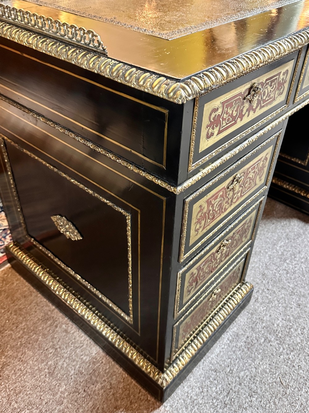 An ebonised French pedestal desk featuring red tortoiseshell and brass Boulle marquetry inlay, multiple drawers, a leather writing top, and a brass gallery. View XIV
