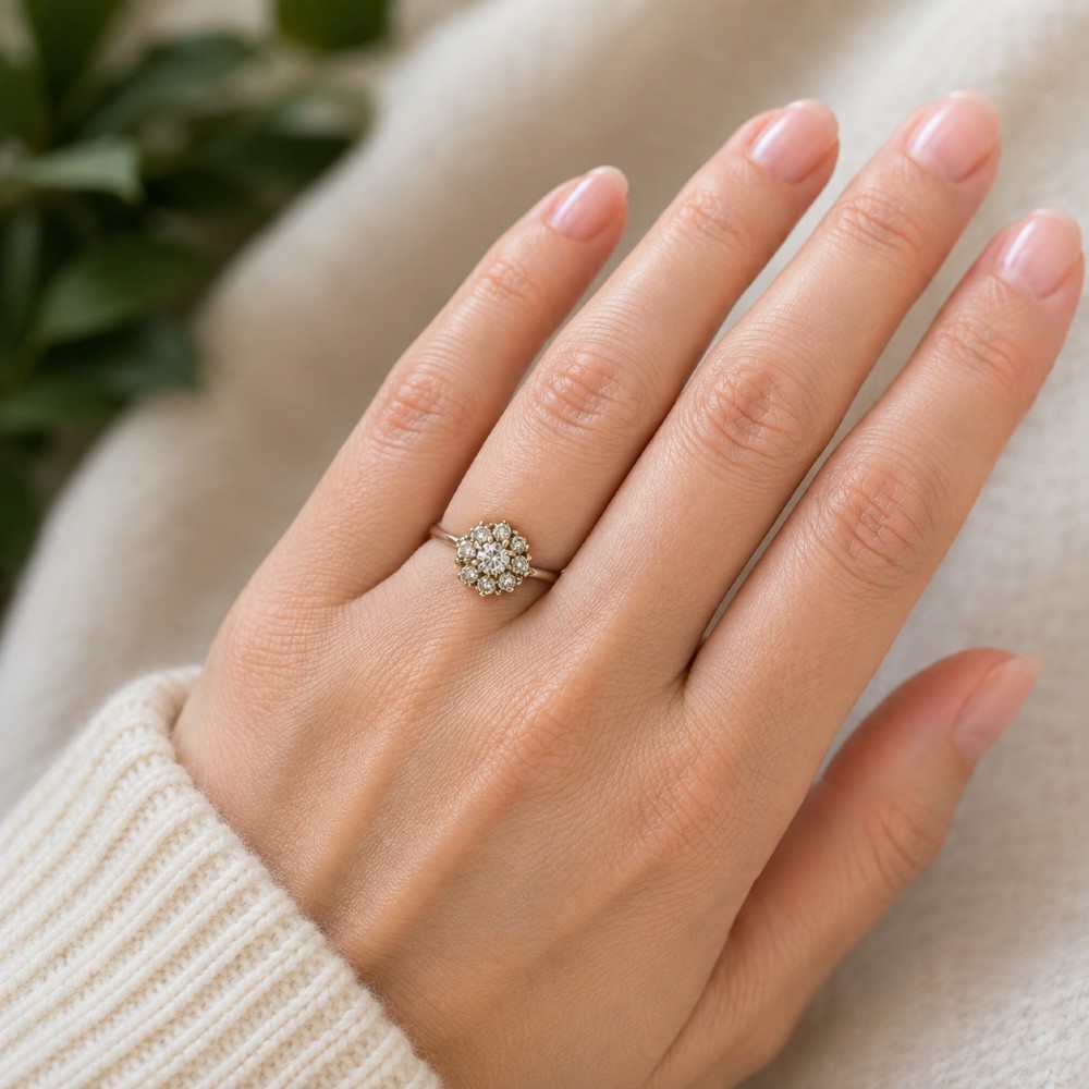 A platinum ring featuring a central round diamond encircled by eight smaller diamonds in a raised cluster setting. View VII