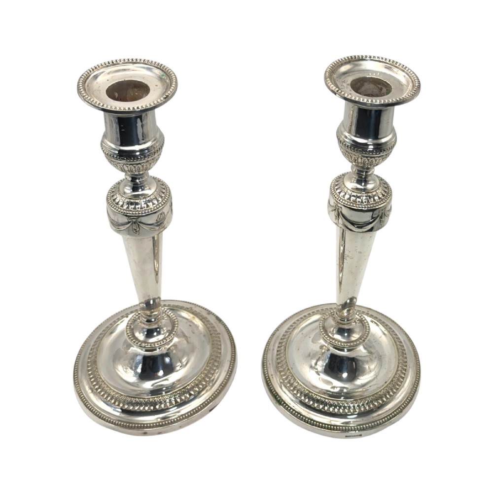 A pair of silver-plated candlesticks with tapered shafts, classical drapery swag motifs, and beaded circular bases. View III