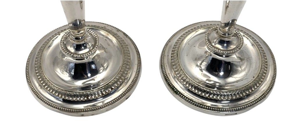 A pair of silver-plated candlesticks with tapered shafts, classical drapery swag motifs, and beaded circular bases. View V