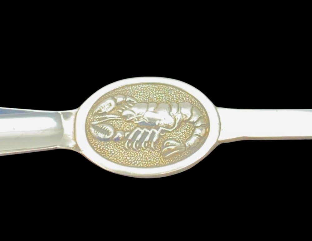 A set of six silver-plated lobster forks with slim double tines and oval medallions embossed with lobster designs on the handles. View V