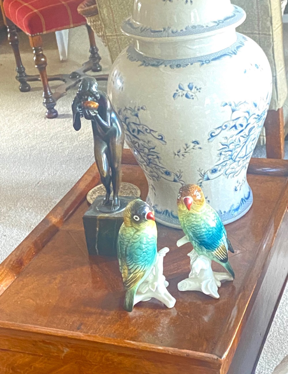 A pair of glazed porcelain parrot figurines featuring detailed green and brown feather moulding perched on off-white branch bases. View VII