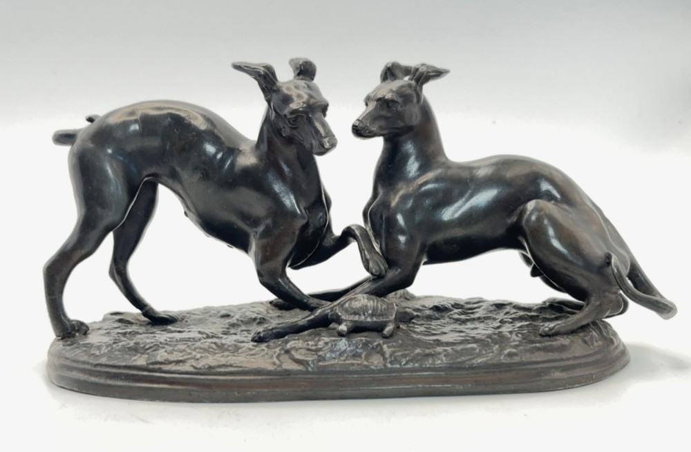 An antique dark brown spelter sculpture depicting two playing greyhounds positioned over a small tortoise on an oval base. View II