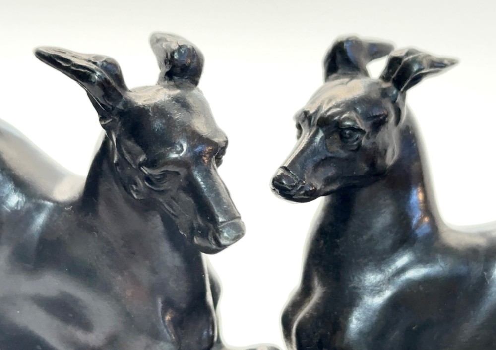 An antique dark brown spelter sculpture depicting two playing greyhounds positioned over a small tortoise on an oval base. View III