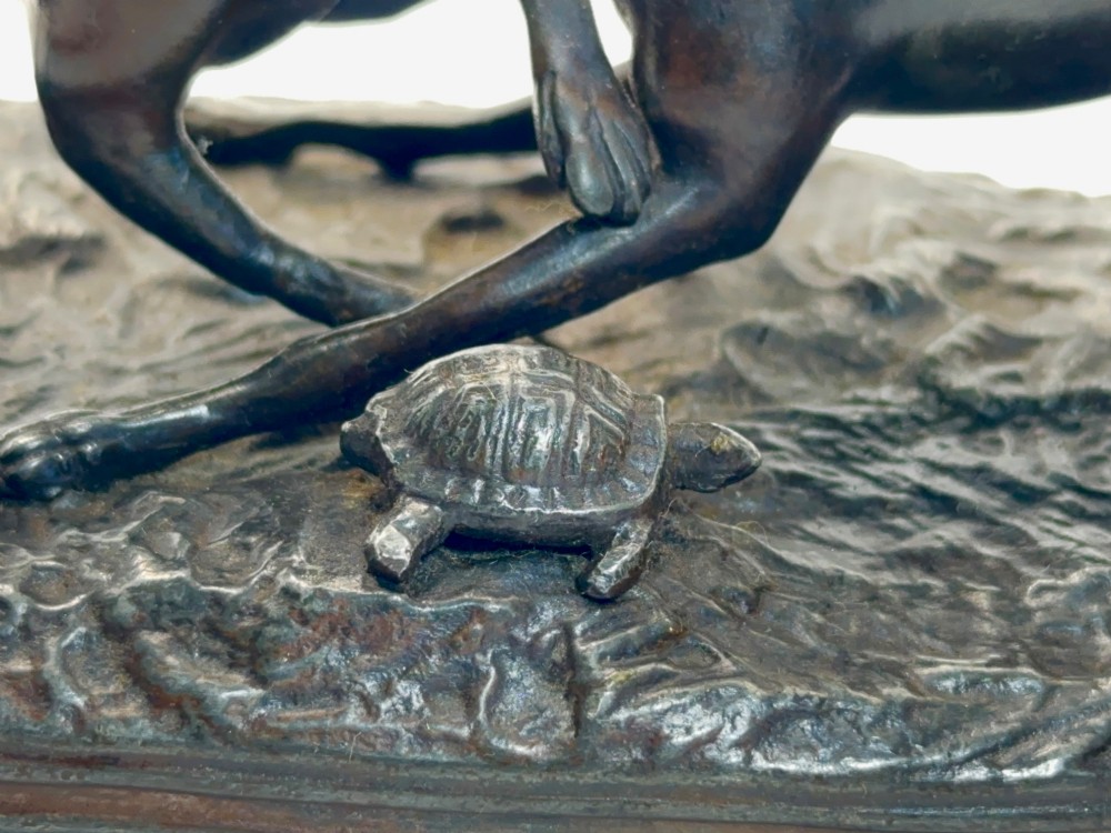 An antique dark brown spelter sculpture depicting two playing greyhounds positioned over a small tortoise on an oval base. View IV
