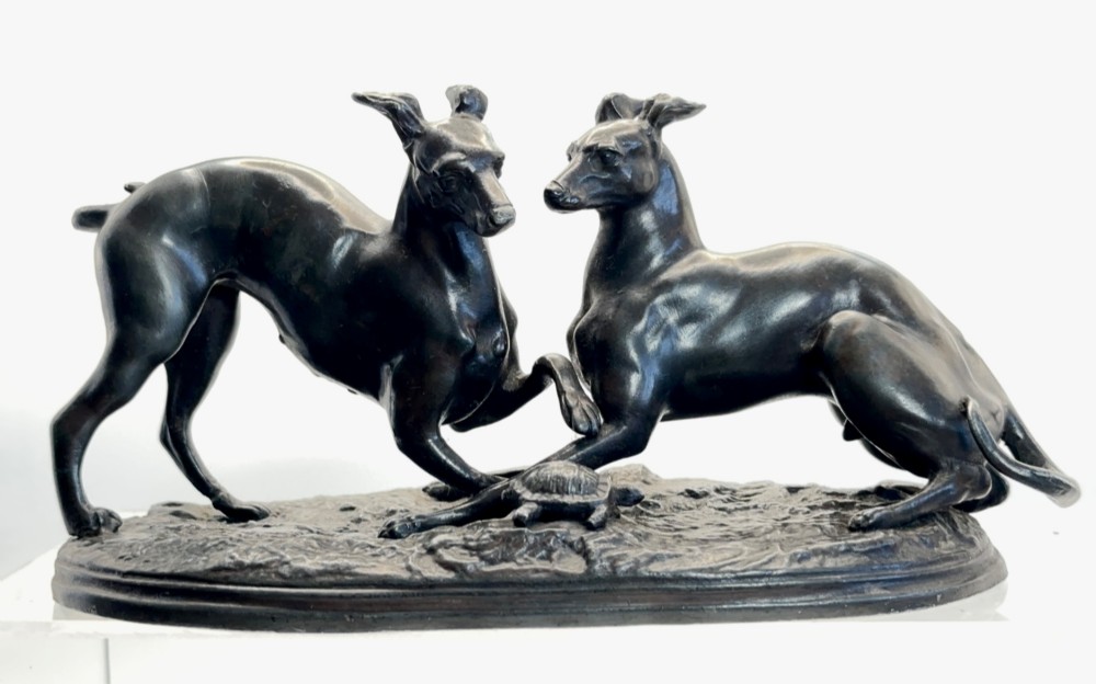 An antique dark brown spelter sculpture depicting two playing greyhounds positioned over a small tortoise on an oval base. View VI