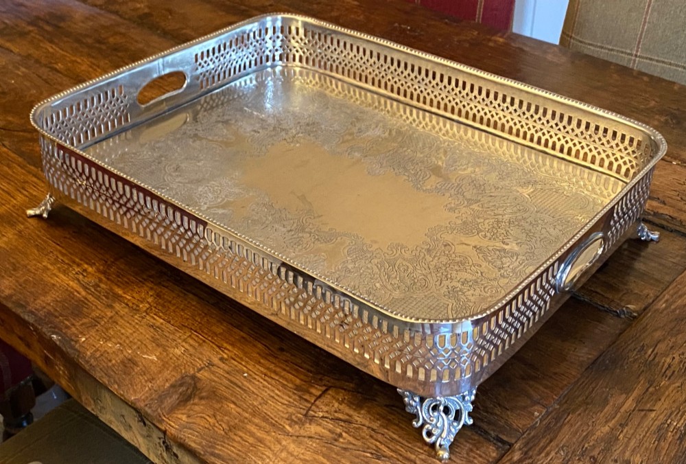 A rectangular silver-plated gallery tray featuring pierced fretwork sides, integrated oval hand-holds, an engraved surface, and ornate scrolled feet. View IV