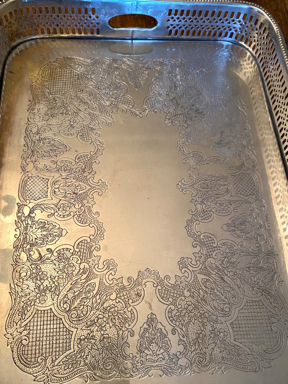 A rectangular silver-plated gallery tray featuring pierced fretwork sides, integrated oval hand-holds, an engraved surface, and ornate scrolled feet. View VIII