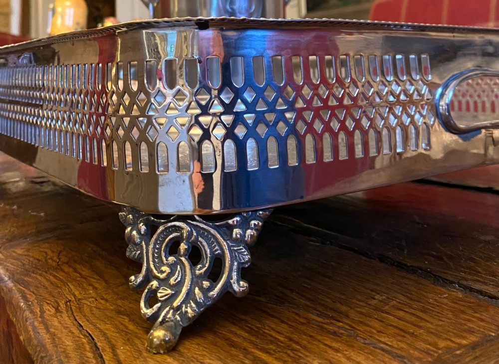 A rectangular silver-plated gallery tray featuring pierced fretwork sides, integrated oval hand-holds, an engraved surface, and ornate scrolled feet. View XIV