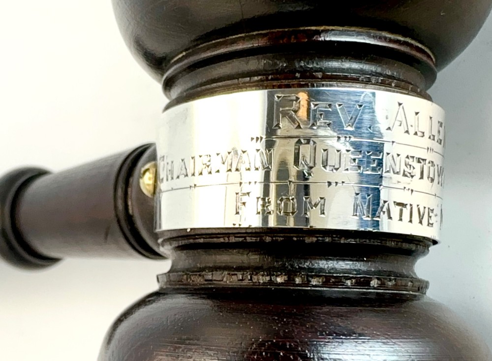 A turned dark wood ceremonial gavel featuring a central silver presentation band secured with small screws. View III