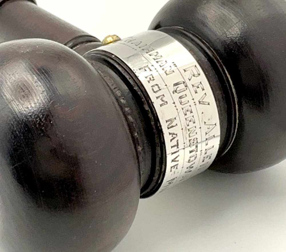 A turned dark wood ceremonial gavel featuring a central silver presentation band secured with small screws. View IV