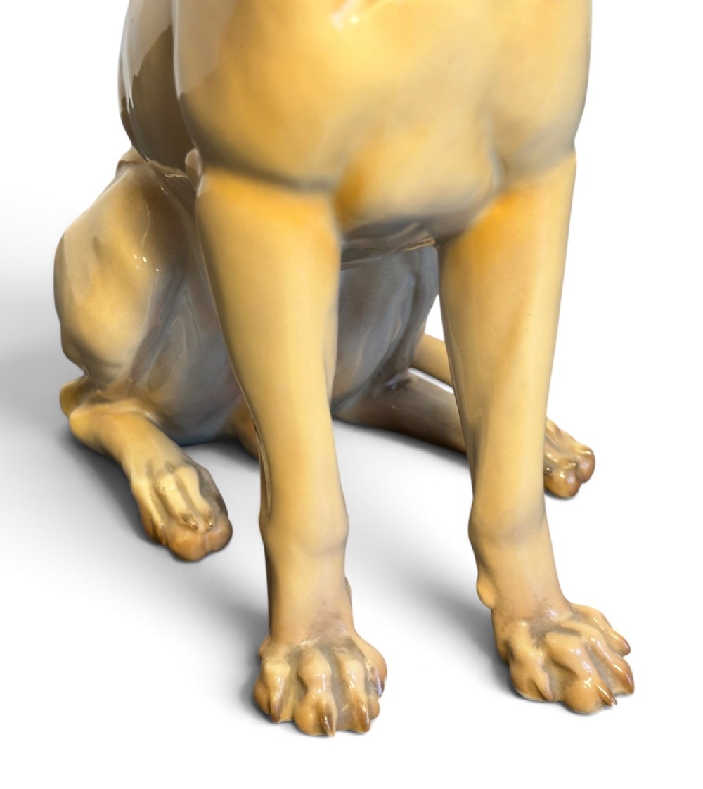 A glazed fawn-coloured Nymphenburg porcelain figurine depicting a seated Great Dane with erect ears and a black muzzle. View VII