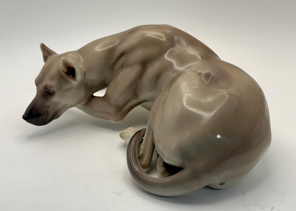 A glazed Nymphenburg porcelain figurine depicting a recumbent Great Dane dog in taupe grey and neutral tones. View II