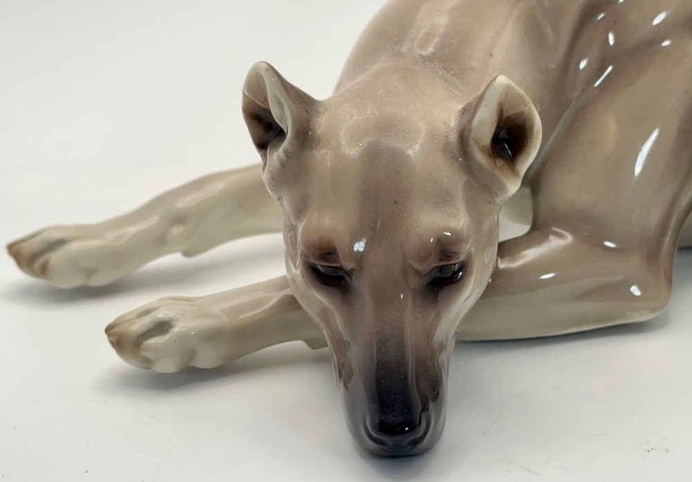 A glazed Nymphenburg porcelain figurine depicting a recumbent Great Dane dog in taupe grey and neutral tones. View IV