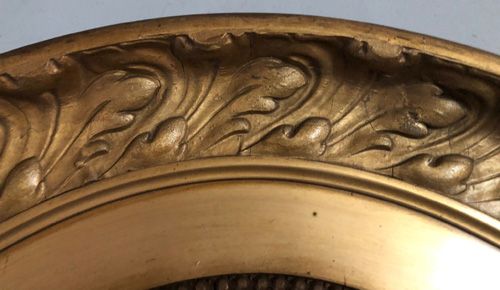 fig 1. A large oval wall mirror featuring a gilded wooden frame with relief acanthus leaf carving and a beaded inner border.