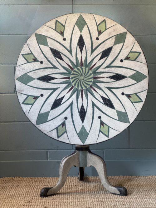 fig 1. A Victorian circular tilt-top table with a turned tripod pedestal base and hand-painted geometric petal design in green, cream, and black.