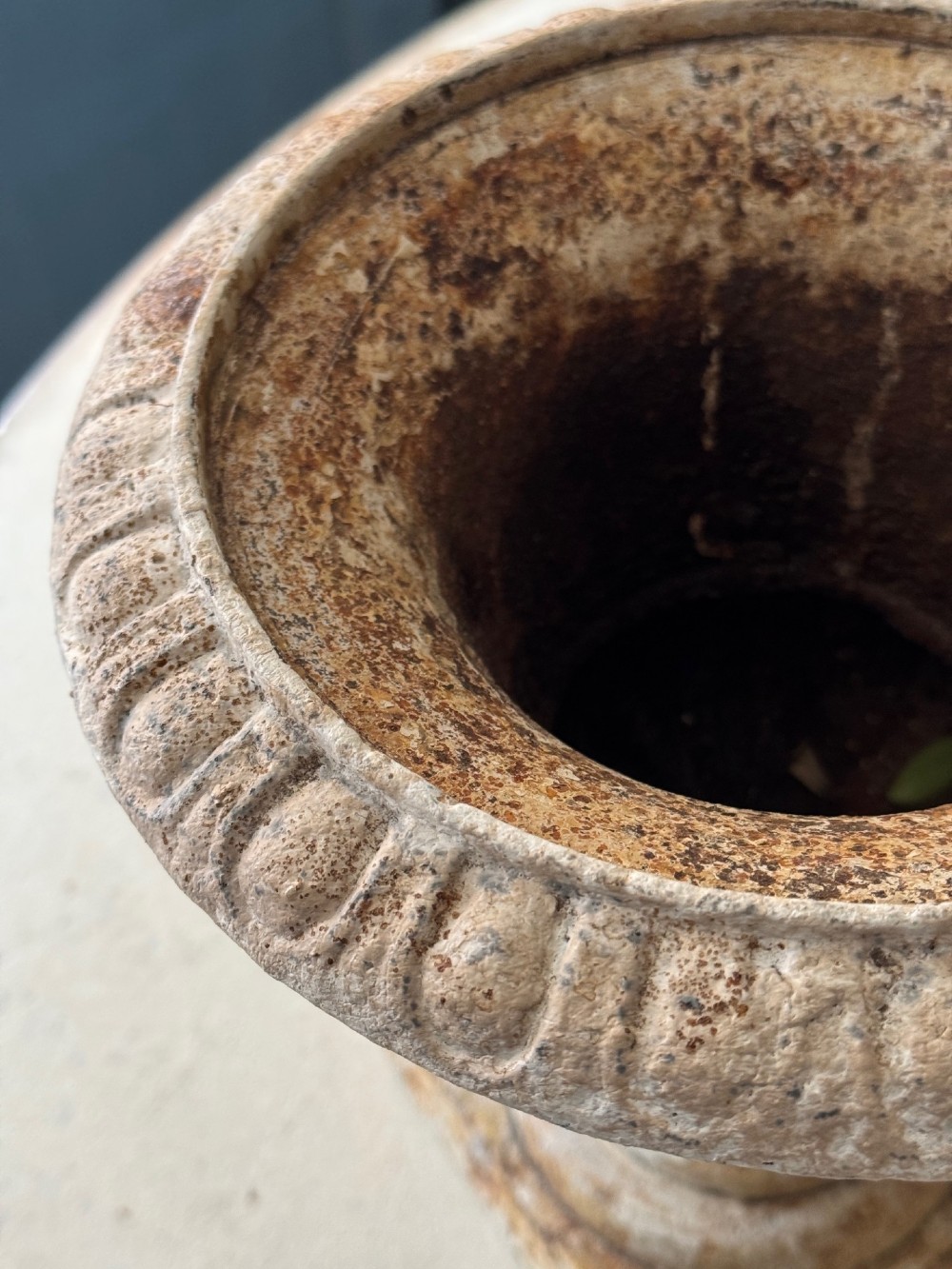 A pair of antique French cast iron garden urns with fluted bodies, square bases, and weathered off-white painted finishes showing natural rust patina. View V