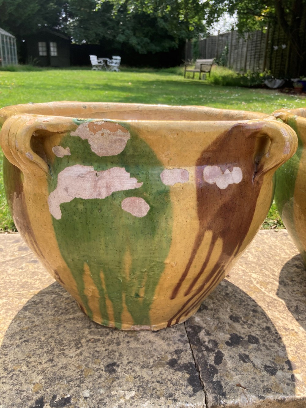A pair of round ochre yellow terracotta planters featuring green and brown drip glaze patterns and twin looped side handles. View VI