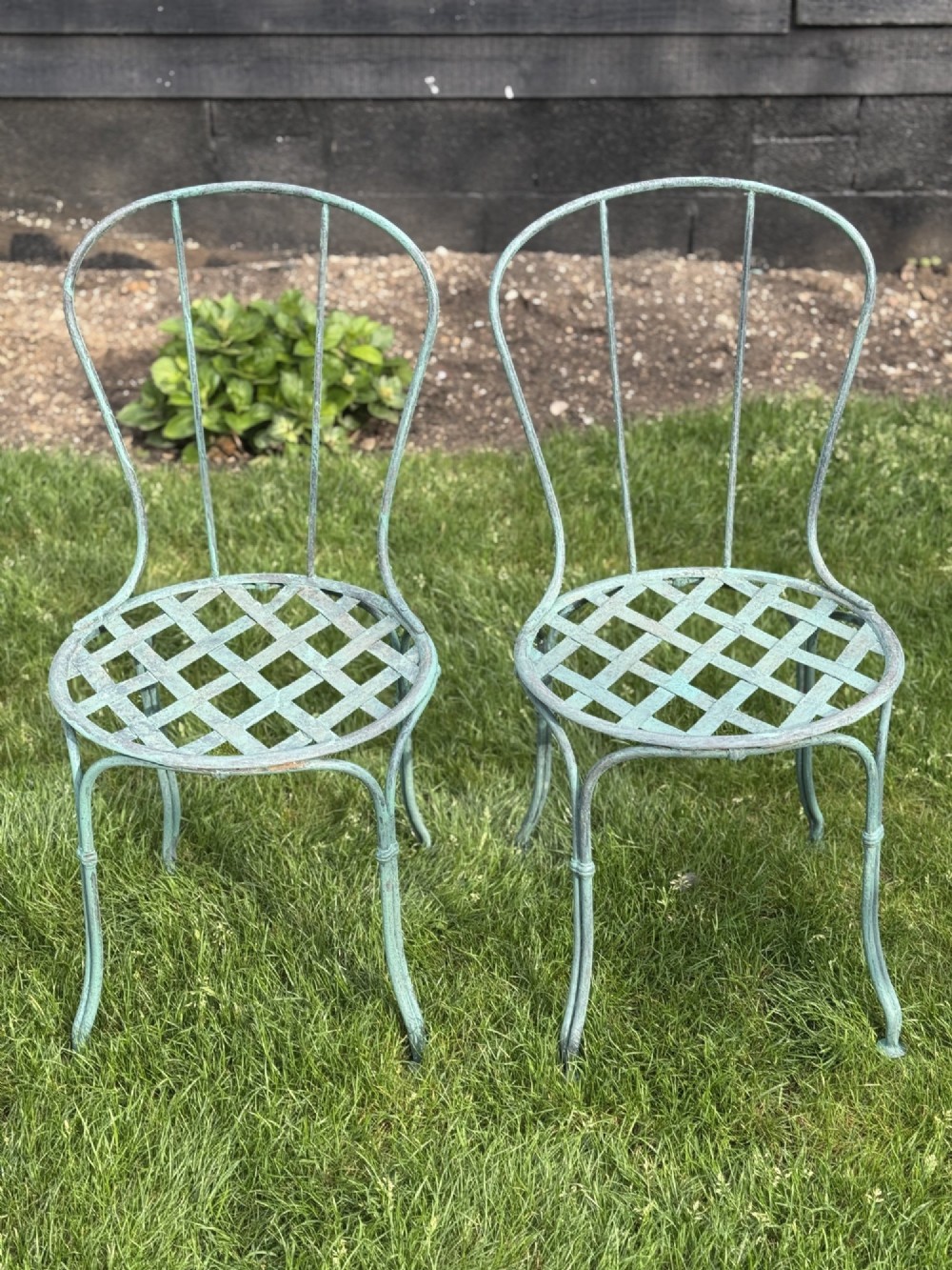 A weathered green painted wrought iron bistro set featuring a round pedestal table and two hoop-back chairs with lattice seats. View III
