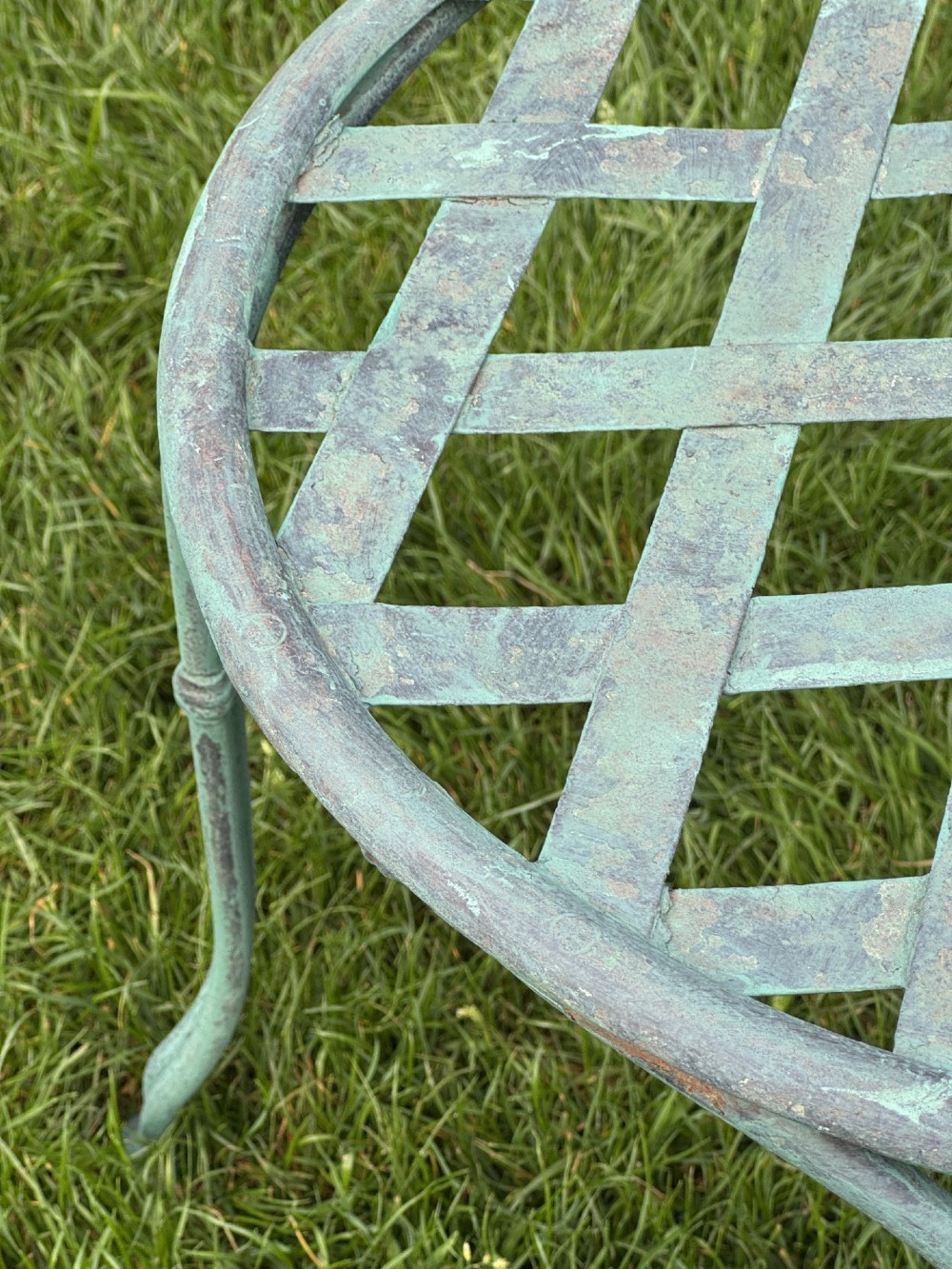 A weathered green painted wrought iron bistro set featuring a round pedestal table and two hoop-back chairs with lattice seats. View VIII