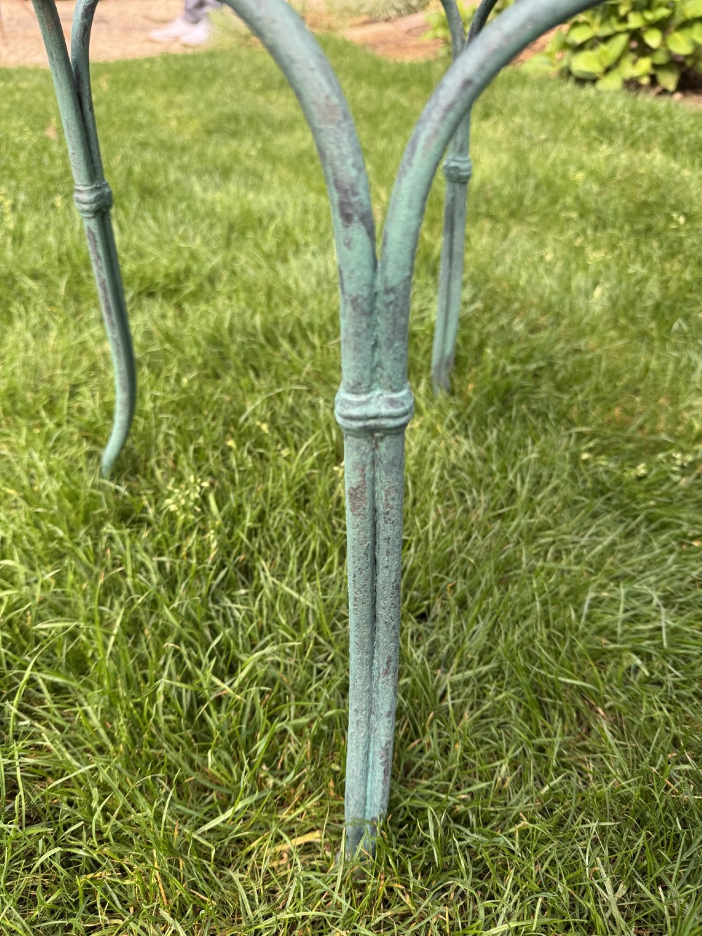A weathered green painted wrought iron bistro set featuring a round pedestal table and two hoop-back chairs with lattice seats. View IX