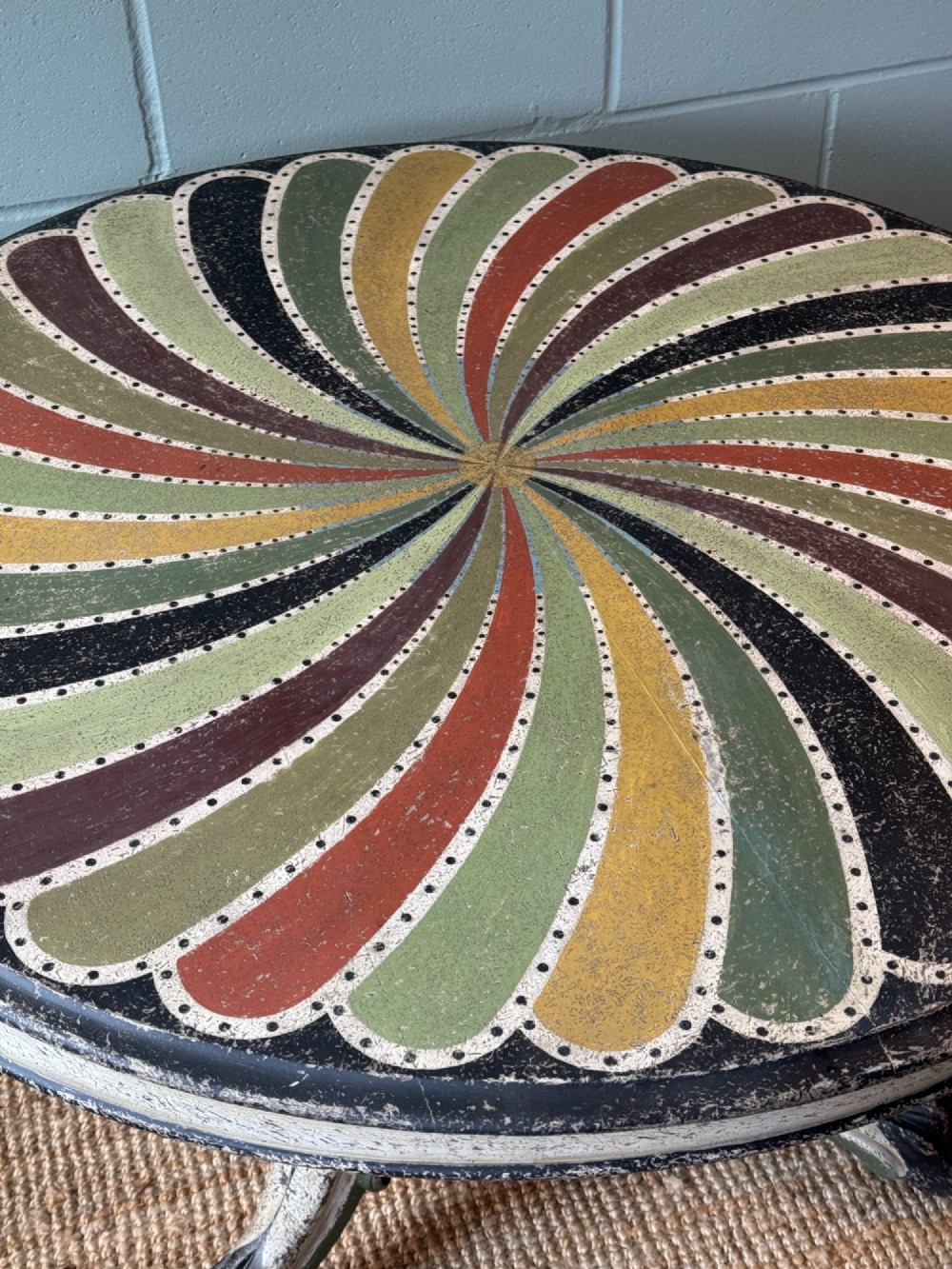 A Victorian circular tilt-top table featuring a hand-painted swirling polychrome petal pattern across its surface, resting on a distressed carved tripod base. View III