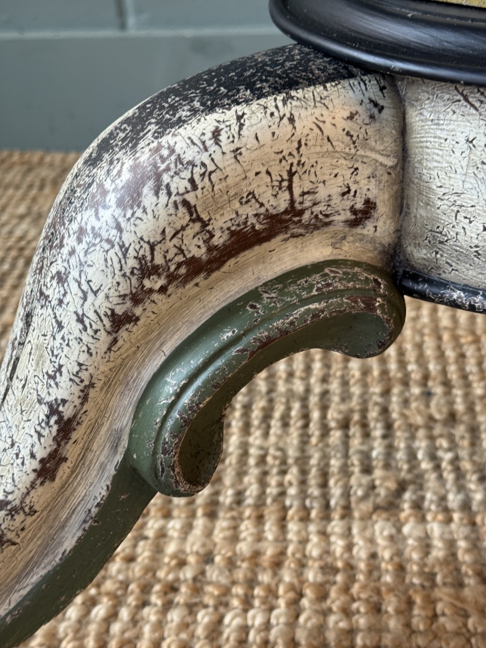 A Victorian circular tilt-top table featuring a hand-painted swirling polychrome petal pattern across its surface, resting on a distressed carved tripod base. View V