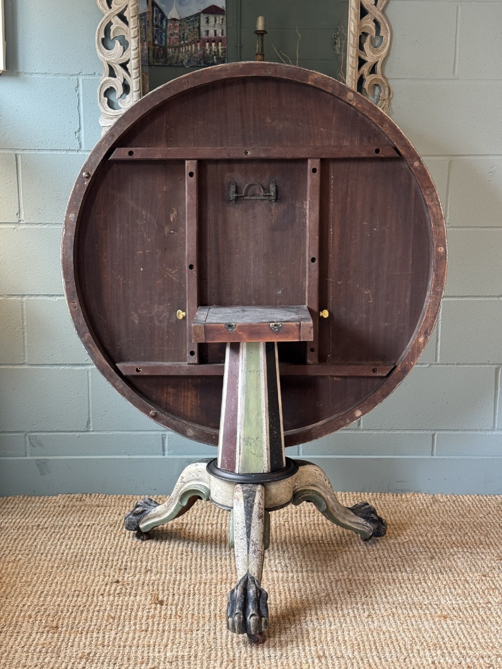 A Victorian circular tilt-top table featuring a hand-painted swirling polychrome petal pattern across its surface, resting on a distressed carved tripod base. View VII