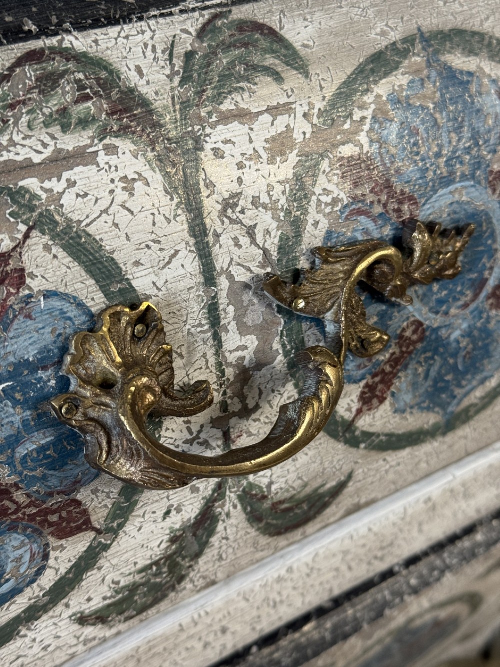 A nineteenth-century French bombee chest of drawers featuring a later hand-painted pattern, a dark marble top, and ornate gilt bronze mounts. View III