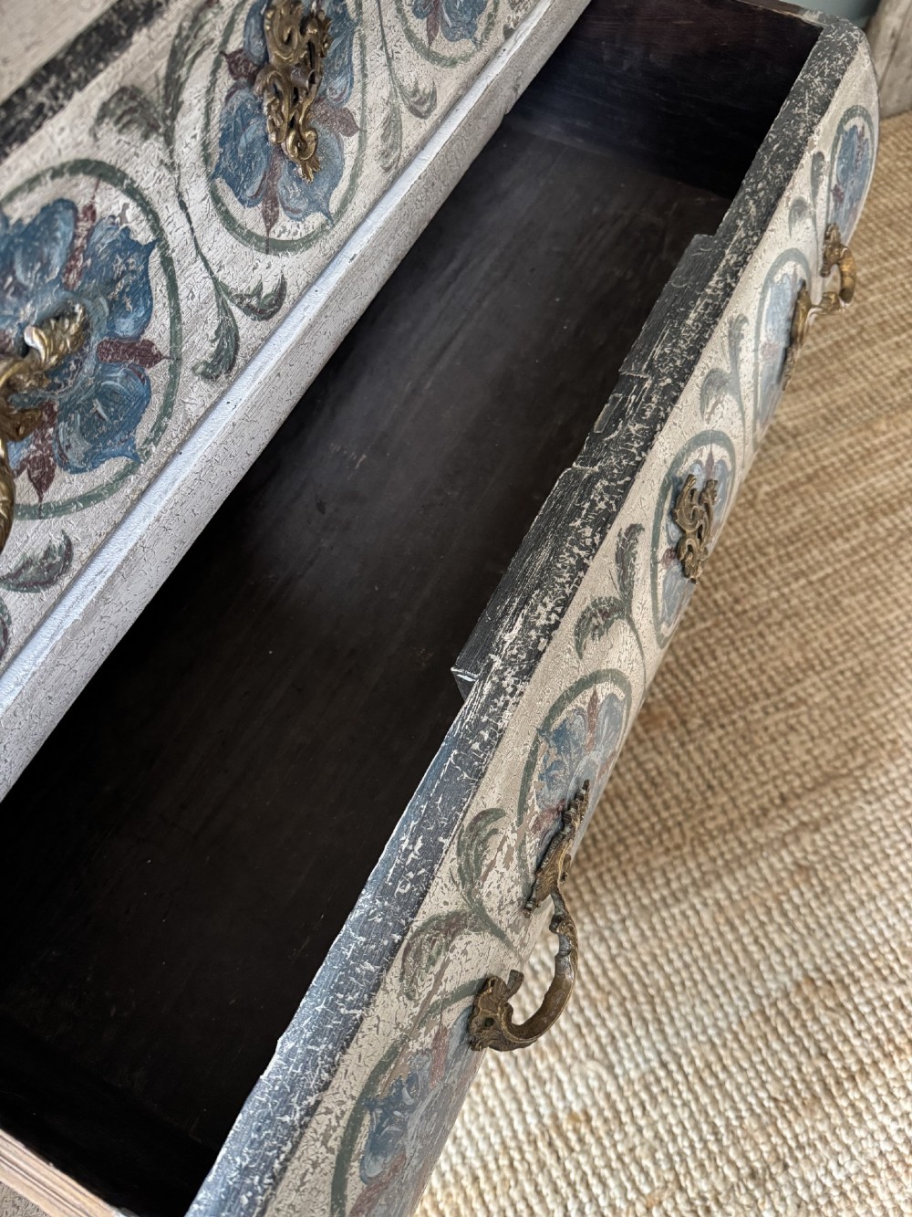 A nineteenth-century French bombee chest of drawers featuring a later hand-painted pattern, a dark marble top, and ornate gilt bronze mounts. View XI