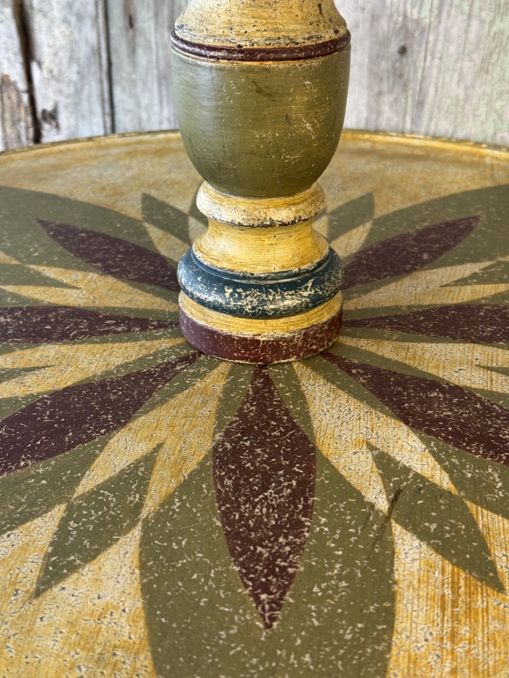 A Victorian three-tier wooden pedestal table with a painted finish, turned central stem, starburst motif, and tripod feet. View V