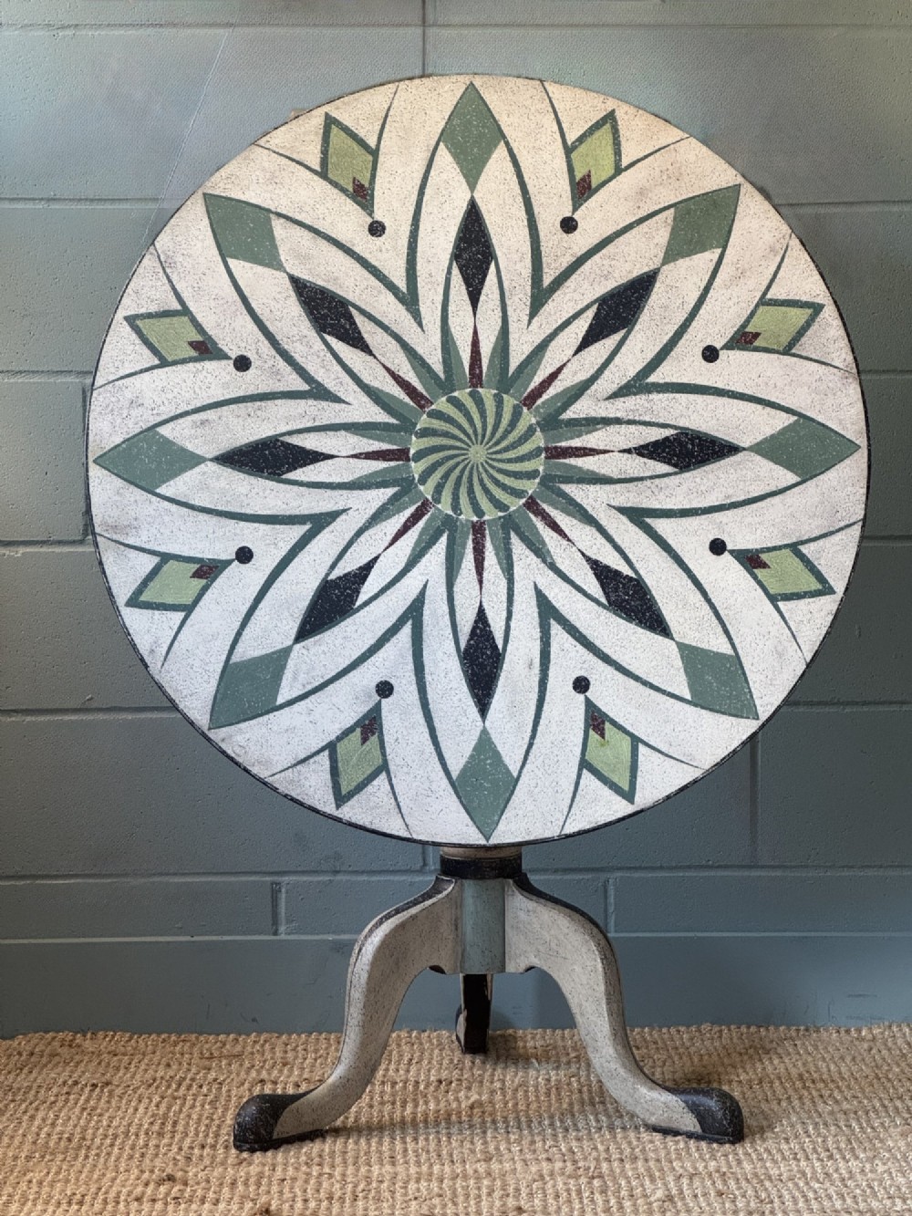A Victorian circular tilt-top table with a turned tripod pedestal base and hand-painted geometric petal design in green, cream, and black. View II