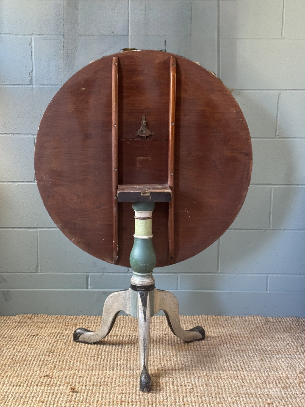 A Victorian circular tilt-top table with a turned tripod pedestal base and hand-painted geometric petal design in green, cream, and black. View VII