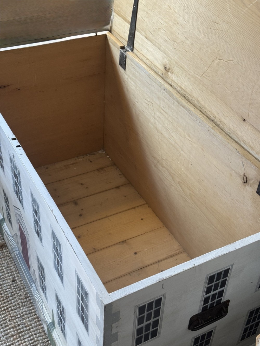 An off-white wooden blanket box hand-painted with a detailed depiction of a Georgian manor house facade featuring a central red door, sash windows, and stone steps. View V