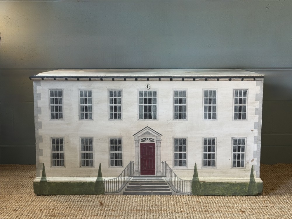 An off-white wooden blanket box hand-painted with a detailed depiction of a Georgian manor house facade featuring a central red door, sash windows, and stone steps.